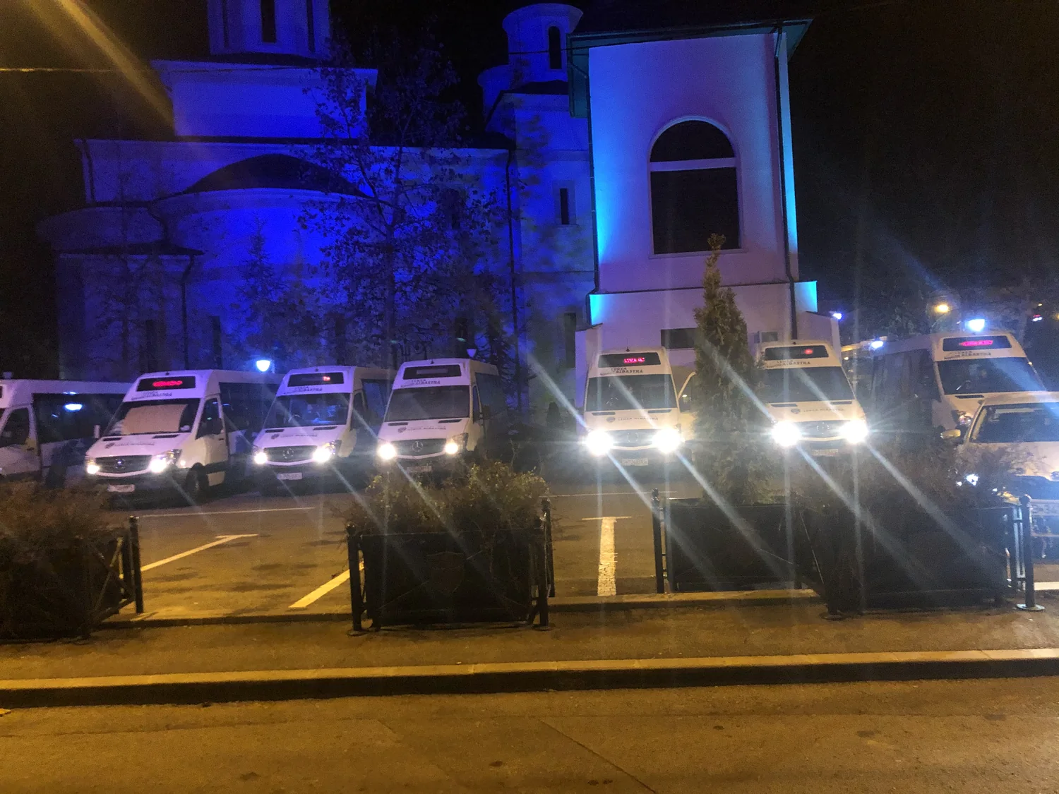 Vehiculele Linia Albastră parcate seara, cu afișajele de destinație aprinse